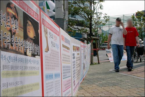 미군범죄 홍보물 옆을 지나가는 미군들 